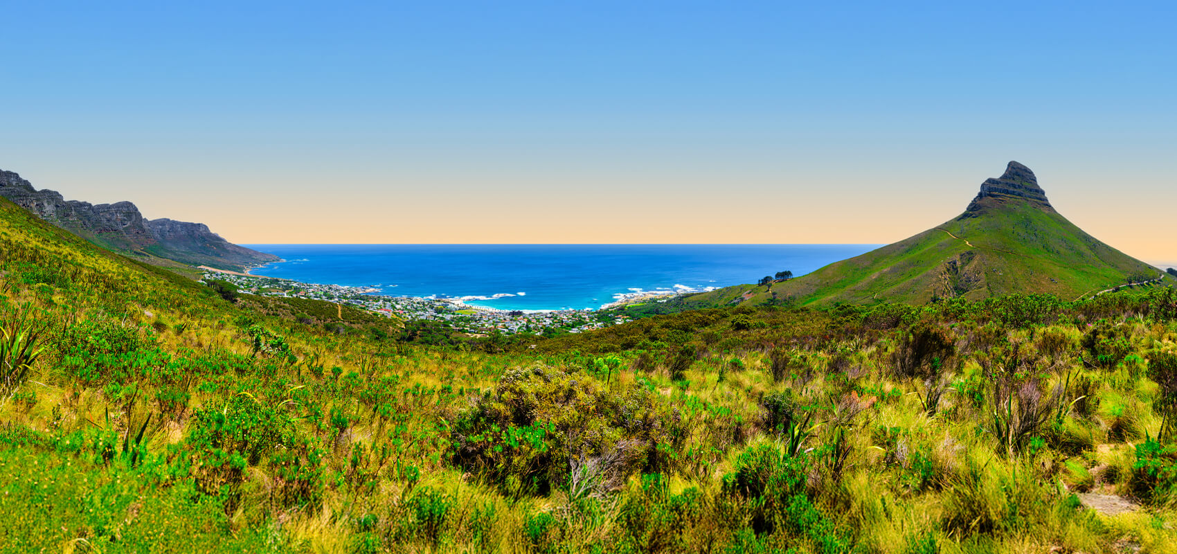 View from Table Mountain summit showing the 12 Apostles mountain range, Lion's Head, and the Atlantic Ocean.